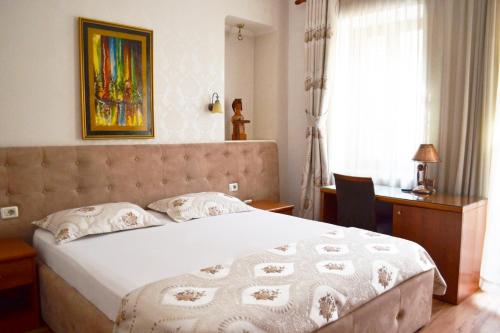 a bedroom with a bed and a desk and a window at Hotel Villa Tafaj in Tirana