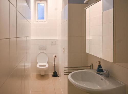 ein weißes Bad mit einem WC und einem Waschbecken in der Unterkunft Elegant Suite Augarten in Wien