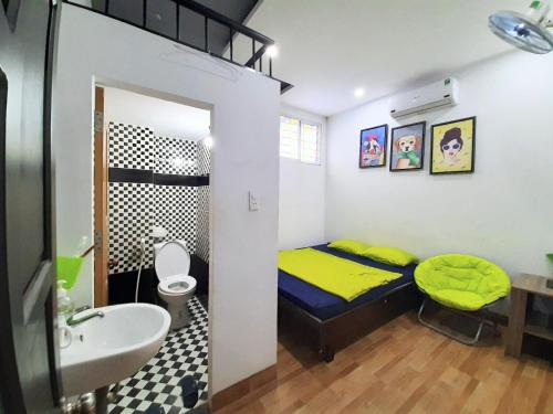 Cette petite chambre comprend un lit jaune et un lavabo. dans l'établissement Homestay Xì Trum, à Đà Nẵng