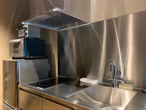 a stainless steel kitchen with a sink and a microwave at Gion Suite in Kyoto