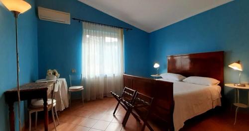 a bedroom with blue walls and a bed and a table at Fabiola B & B in Marino
