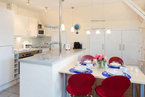 una cocina con sillas rojas y una mesa con comida en FEWO Ringelblume, en List