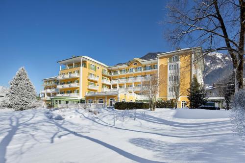 a large yellow building with snow on the ground at Das Alpenhaus Gasteinertal in Bad Hofgastein