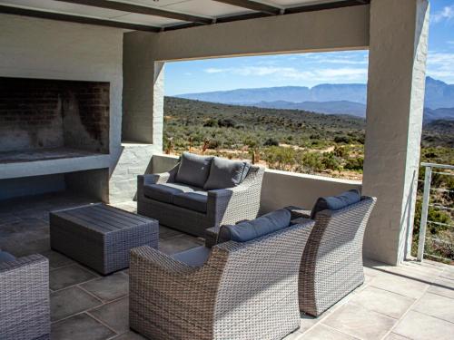 a patio with a couch and chairs and a fireplace at Rooiberg Wild Private Game Reserve in Ladismith