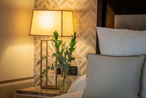 a vase of flowers on a table next to a bed at Hospes Palacio de Arenales & Spa in Cáceres