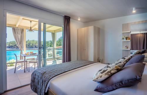 a bedroom with a bed and a balcony with a table at Valamar Camping Ježevac in Krk