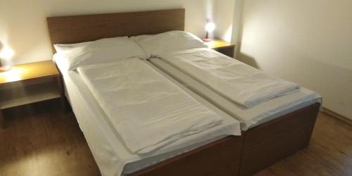 a bed with white sheets on it in a room at Aparthotel Rezidence Club Canada Lipno in Lipno nad Vltavou