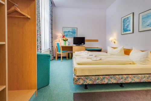 マイセンにあるHotel Alte Klavierfabrik Meißenのベッドとデスクが備わるホテルルームです。