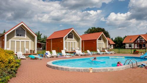 a couple of people in a swimming pool with houses at Ośrodek Wypoczynkowy Mewa in Jantar