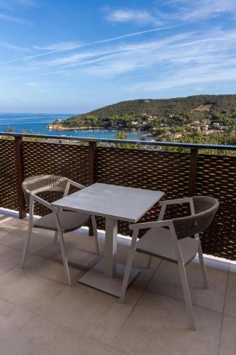 a table and chairs on a balcony with the ocean at Hotel La Perla Del Golfo in Procchio