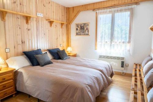 um quarto com uma cama grande num quarto com paredes de madeira em La Marmota Suite apartamento rústico en Panticosa em Panticosa