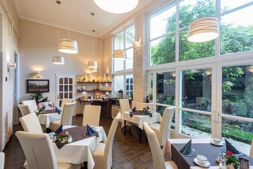 a restaurant with tables and chairs and windows at Hotel Romantik Eger in Eger