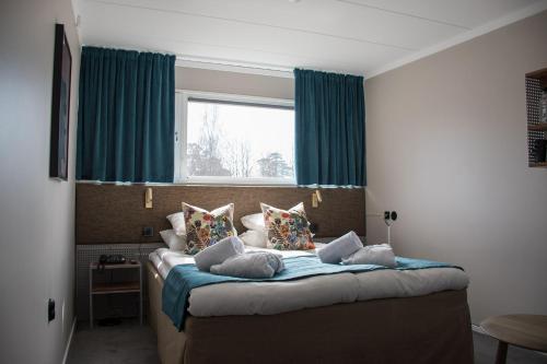 a bedroom with a bed with blue curtains and a window at Sigtunahöjden Hotell & Konferens in Sigtuna