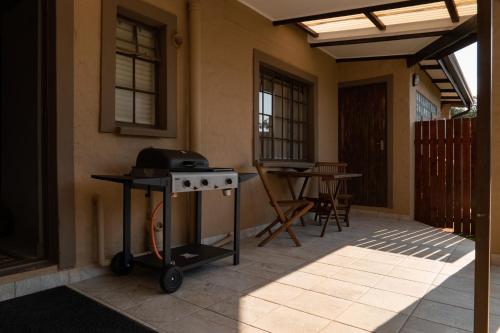 a grill on a patio with a table and chairs at Camdeboo Place in Dullstroom
