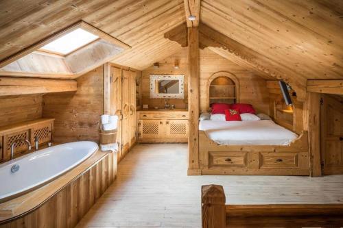 Cette chambre en bois comprend une salle de bains pourvue d'un lit et d'une baignoire. dans l'établissement Les Gentianes Appartement 5 personnes à 50 mètres des pistes Meribel 3 vallées, à Méribel