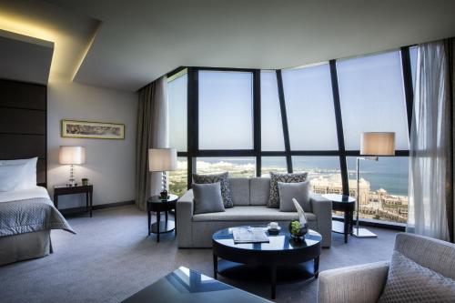 a hotel room with a bed and a couch and a large window at Bab Al Qasr Hotel in Abu Dhabi