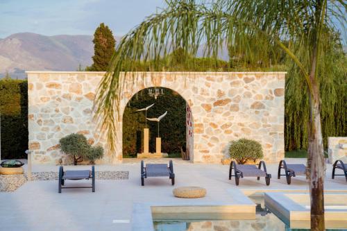 a courtyard with benches and a stone wall at Villa Shangri-La Zakinthos in Zakynthos Town
