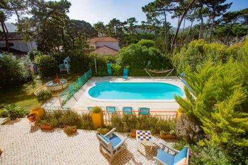 a swimming pool in a yard with chairs and trees at A Barca Charm House in Sintra