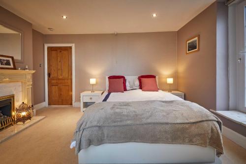 a bedroom with a bed with red pillows and a fireplace at Host & Stay - The View Old Coastguard Cottage in Tynemouth