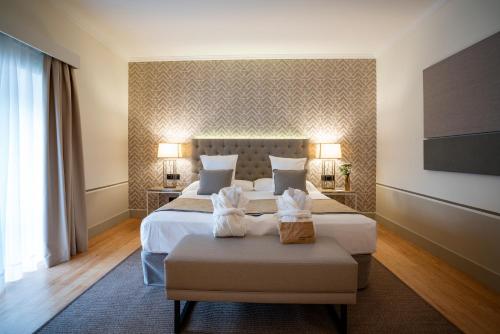 a hotel room with two beds and two chairs at Hospes Palacio de Arenales & Spa in Cáceres