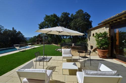 a patio with white chairs and an umbrella at Villa Paradiso in Mensano