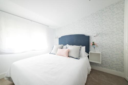 a bedroom with a white bed with a blue headboard at Apartamentos San Francisco - Centrico in Mota del Cuervo