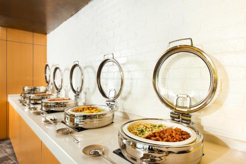 a row of pans of food on a counter with mirrors at Holiday Inn Express Macau City Centre by IHG in Macau
