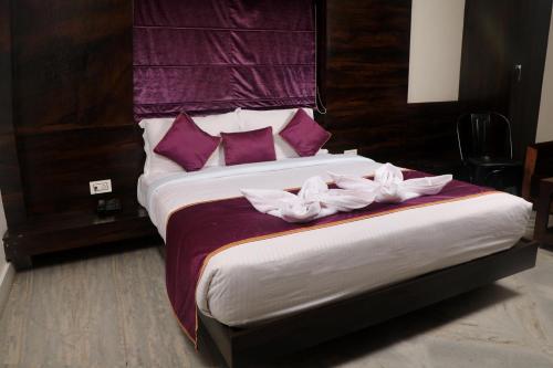 a bedroom with a large bed with purple pillows at Hotel Planet Four in Lonavala