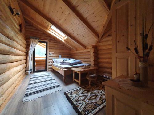 Zimmer mit einem Bett und einem Schreibtisch in einem Blockhaus in der Unterkunft Cabana Raisa in Valea Moldovei