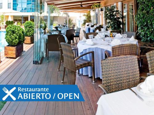 un restaurante al aire libre con mesas y sillas blancas en Best Western Hotel Mediterraneo, en Castelldefels