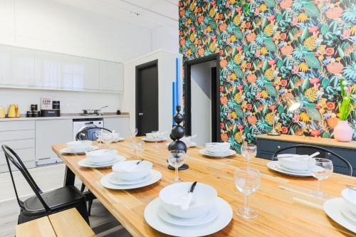 a dining room with a long wooden table with white dishes at The DreamArt Warehouse in London