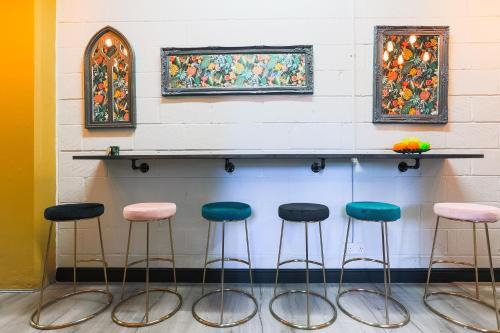 a counter with four stools against a wall with paintings at The DreamArt Warehouse in London