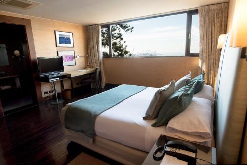 a hotel room with a bed and a desk with a window at Hotel Casa Higueras in Valparaíso