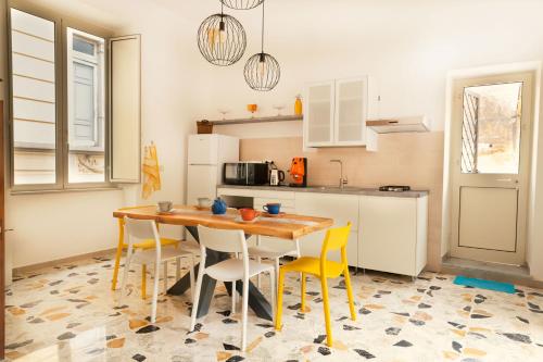a kitchen with a wooden table and yellow chairs at Palazzo Benucci - Residenza di Charme in Santa Maria Capua Vetere