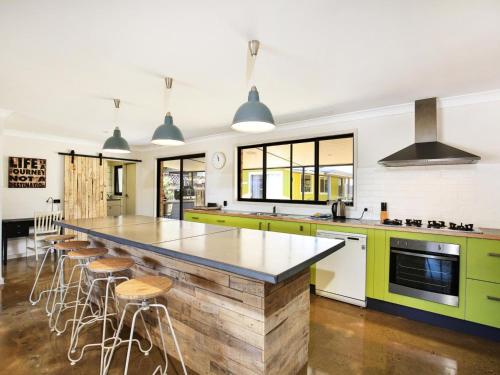 a kitchen with green cabinets and a large island with stools at Aloha - Short Drive to Berry & The Beach - Fireplace and Firepit in Shoalhaven Heads