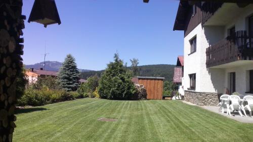 a large yard with chairs and a house at Apartmany U Ády in Železná Ruda