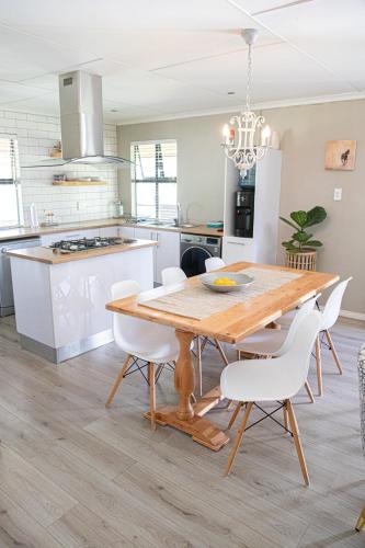 a kitchen with a wooden table and white chairs at Rest at Chabivin in Stellenbosch