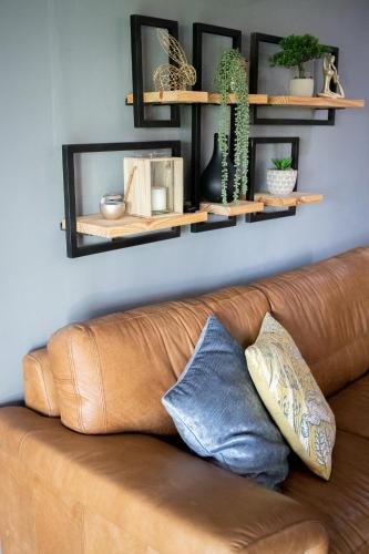 a brown leather couch sitting in a living room with shelves at Rest at Chabivin in Stellenbosch
