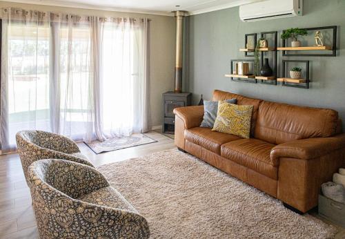 a living room with a brown leather couch and chairs at Rest at Chabivin in Stellenbosch