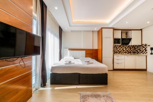 ein Schlafzimmer mit einem Bett und einem TV sowie eine Küche in der Unterkunft TEMA LARA APART in Antalya