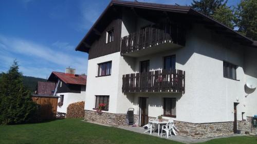 a large white building with balconies and a yard at Apartmany U Ády in Železná Ruda