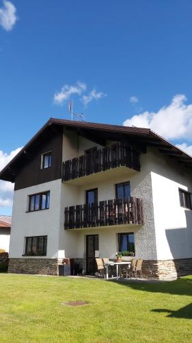 a building with a balcony with a table and chairs at Apartmany U Ády in Železná Ruda