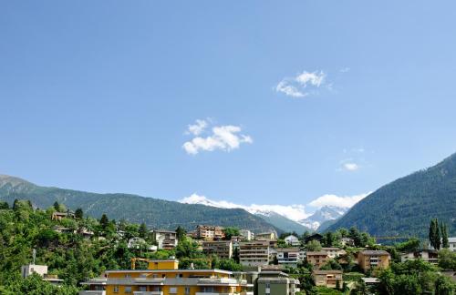 a town on a hill with mountains in the background at Hotel Ambassador in Brig