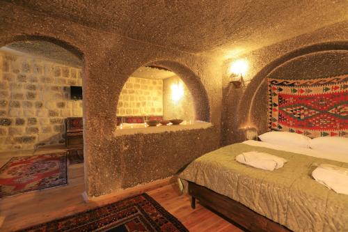 sypialnia z łóżkiem w pokoju z kamiennymi ścianami w obiekcie Antique Terrace Cave Suites w Göreme