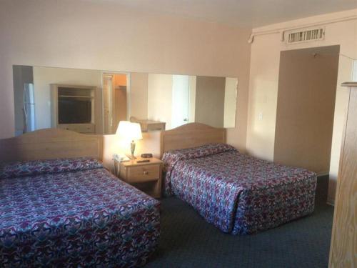 a hotel room with two beds and a lamp at Collins Avenue Hostel in Miami Beach