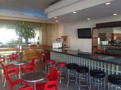 um restaurante com cadeiras e mesas vermelhas e um bar em Collins Avenue Hostel em Miami Beach