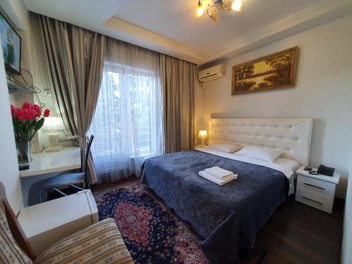 ein Schlafzimmer mit einem Bett, einem Stuhl und einem Fenster in der Unterkunft Bella Donna Hotel in Chişinău