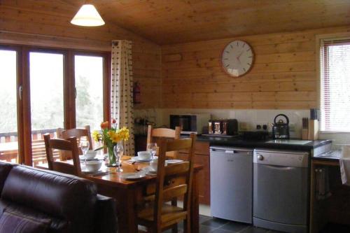 a kitchen with a table and a clock on the wall at Glas Doire Lodge, Glen Roy Nature Reserve in Roybridge