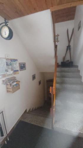 a room with stairs and a clock on the wall at Apartmany U Ády in Železná Ruda