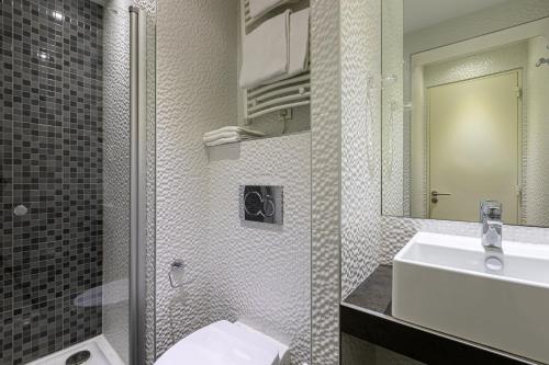 W łazience znajduje się umywalka, toaleta i lustro. w obiekcie Trianon Gare de Lyon w Paryżu